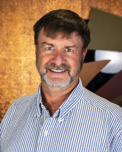 Photograph of Tom Wood showing his face, head, and shoulders with the background from inside the lobby of Timnath Town Hall.