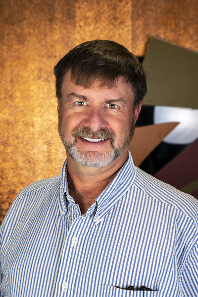 Photograph of Tom Wood showing his face, head, and shoulders with the background from inside the lobby of Timnath Town Hall.