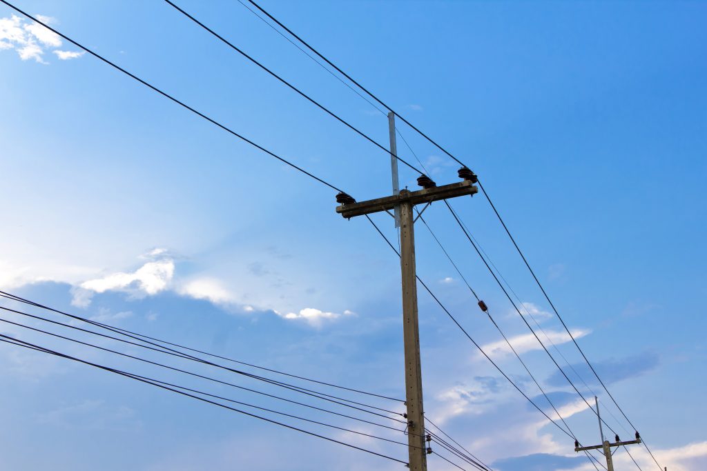 Power poles with a blue sky and clouds behind it.